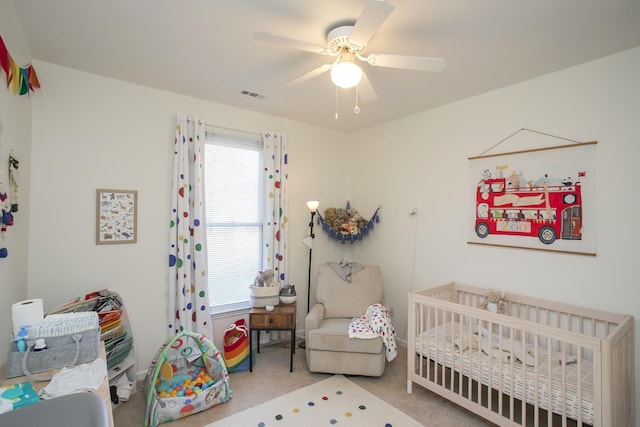 bedroom featuring visible vents, a crib, a ceiling fan, and carpet floors