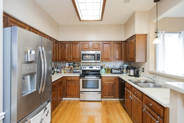 kitchen with brown cabinets, a sink, stainless steel appliances, light countertops, and decorative backsplash