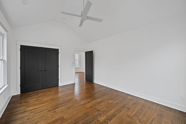 unfurnished bedroom featuring multiple windows, lofted ceiling, baseboards, and dark wood finished floors