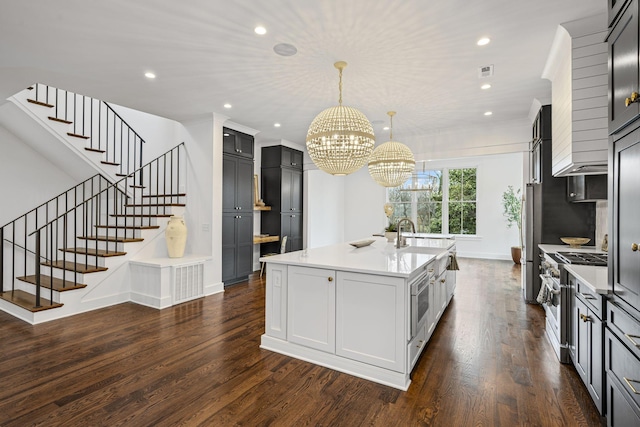 kitchen with a center island with sink, recessed lighting, dark wood-style flooring, stainless steel appliances, and light countertops