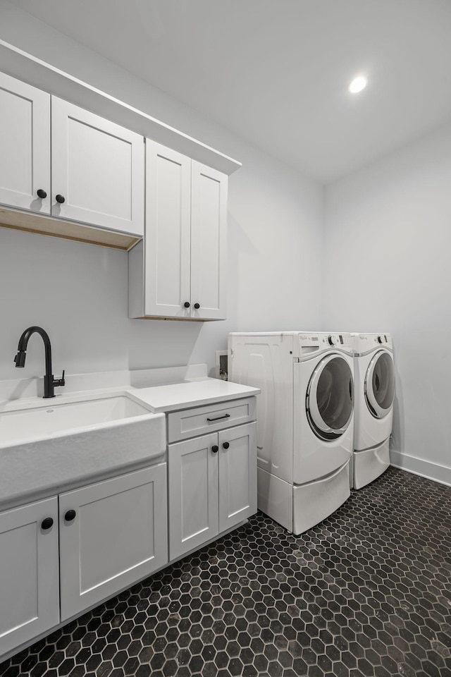 washroom with a sink, baseboards, cabinet space, and washing machine and dryer