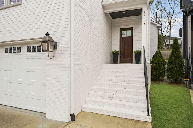 doorway to property with a garage and brick siding