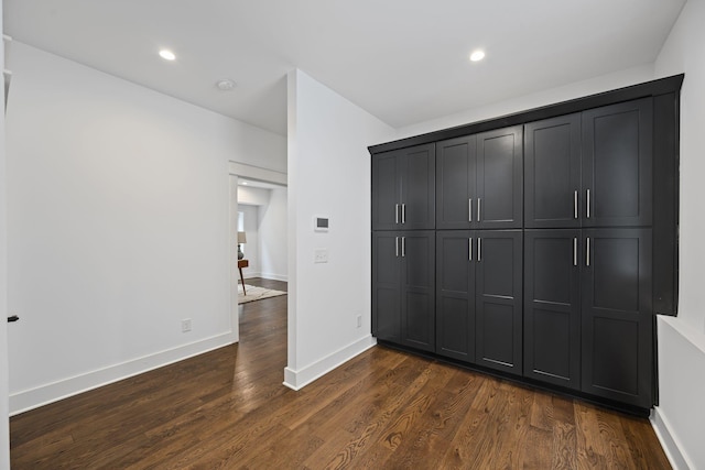 unfurnished bedroom featuring recessed lighting, a closet, baseboards, and dark wood finished floors