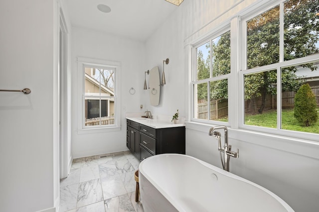 bathroom featuring vanity, a freestanding tub, and marble finish floor