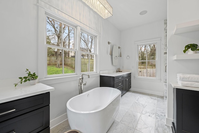 bathroom featuring a soaking tub, marble finish floor, vanity, and baseboards