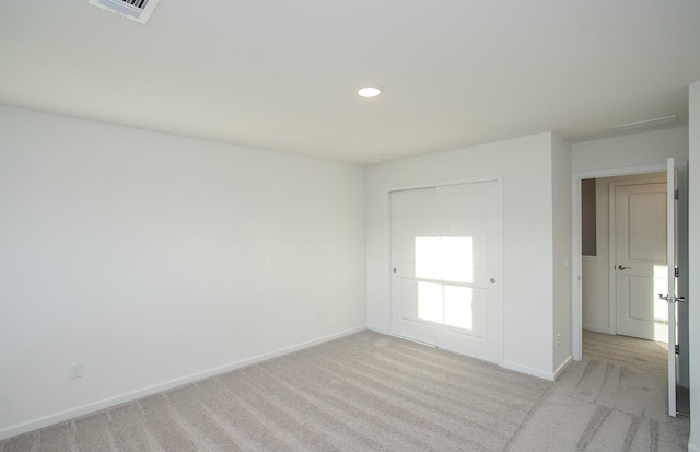 empty room with recessed lighting, visible vents, light colored carpet, and baseboards