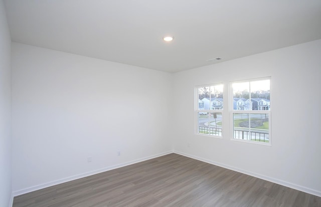 unfurnished room featuring visible vents, recessed lighting, a residential view, baseboards, and dark wood-style flooring