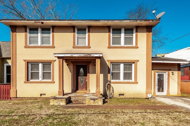 traditional home with crawl space, a front yard, and stucco siding