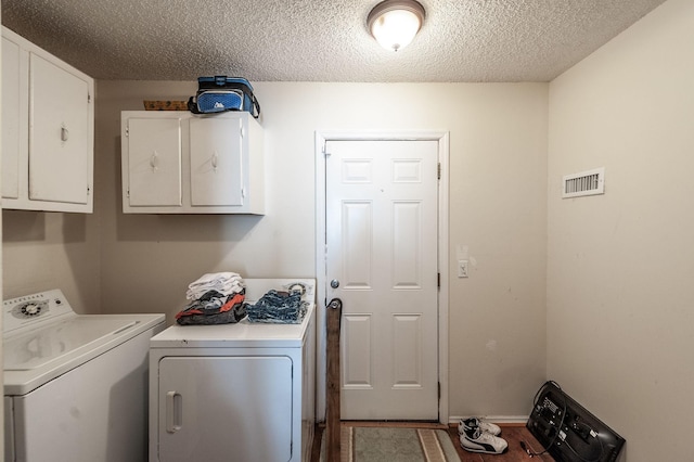 clothes washing area featuring visible vents, cabinet space, a textured ceiling, and washing machine and dryer