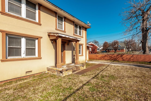 rear view of house with crawl space, a yard, fence, and stucco siding