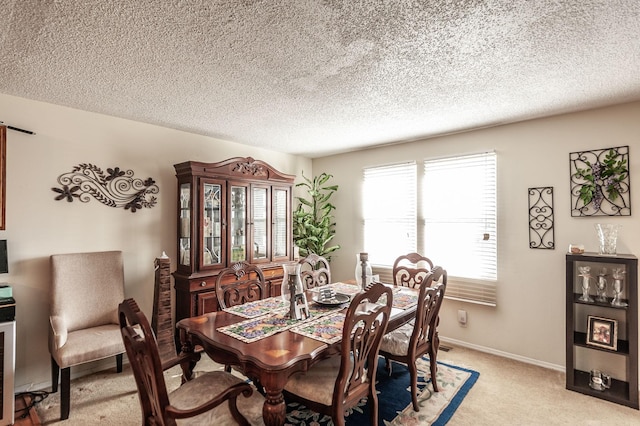 dining area featuring baseboards, light colored carpet, and a textured ceiling