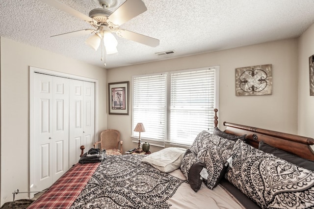 bedroom featuring a closet, a textured ceiling, visible vents, and a ceiling fan