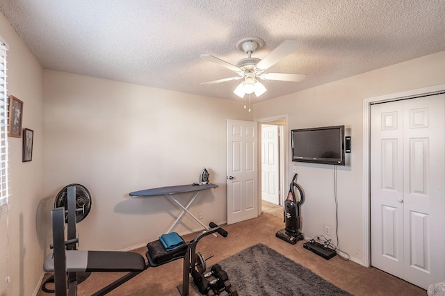 exercise room with baseboards, a textured ceiling, ceiling fan, and carpet floors