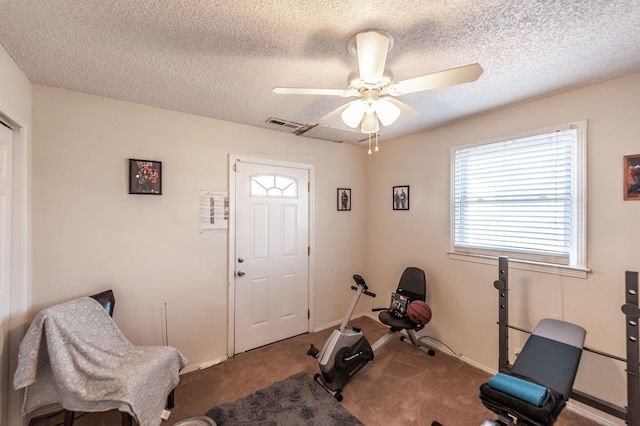 exercise room featuring baseboards, carpet floors, a textured ceiling, and a ceiling fan