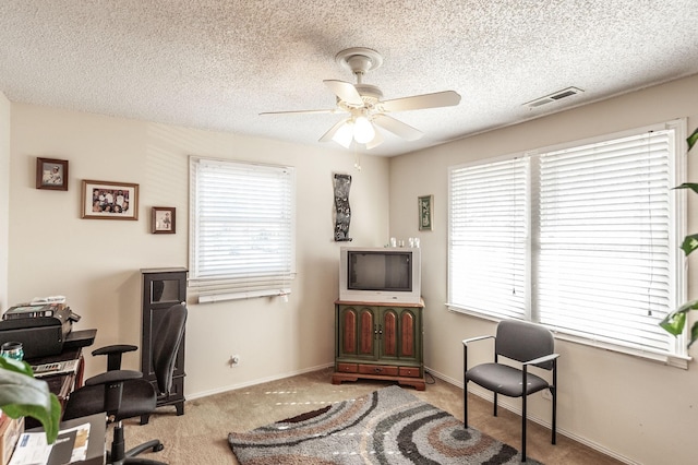 carpeted office with a textured ceiling, baseboards, and a ceiling fan