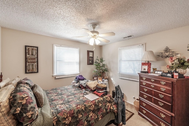 bedroom with light carpet, visible vents, a textured ceiling, and ceiling fan