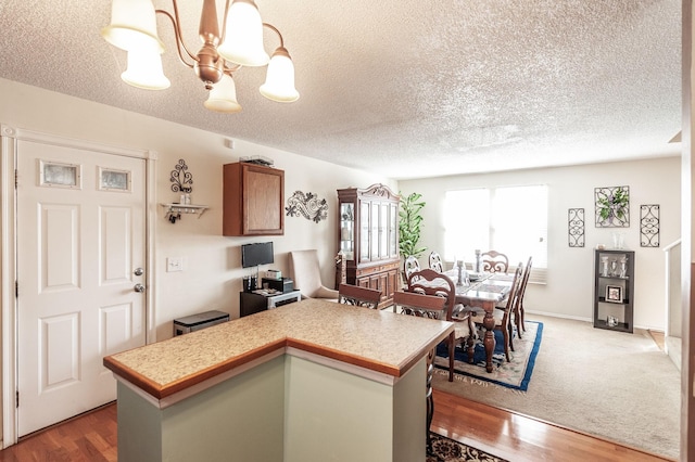 kitchen with a notable chandelier, wood finished floors, a center island, brown cabinetry, and light countertops