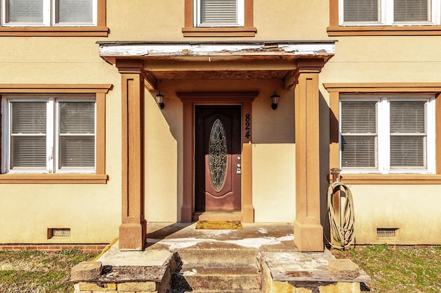 view of exterior entry featuring crawl space and stucco siding