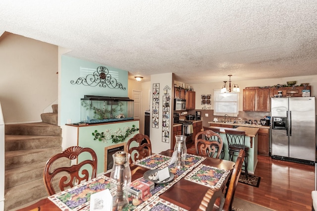 dining space featuring stairs, a notable chandelier, dark wood finished floors, and a textured ceiling