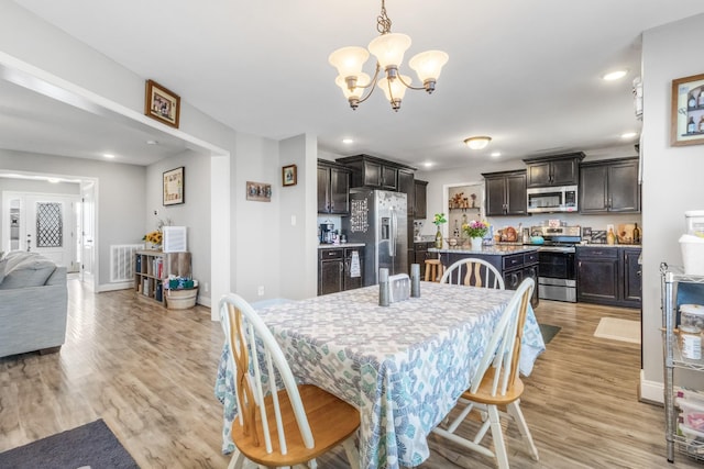 dining room with visible vents, recessed lighting, light wood-type flooring, and an inviting chandelier