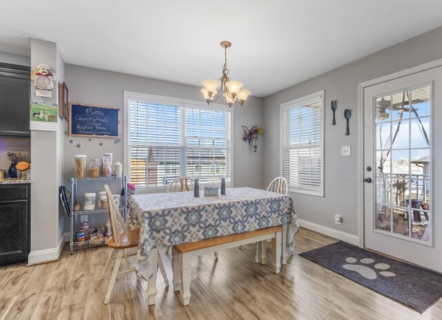 dining area featuring light wood-style flooring, a healthy amount of sunlight, baseboards, and a chandelier