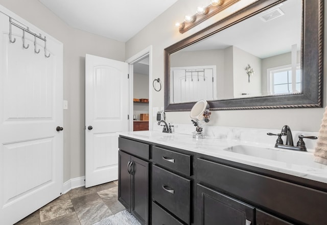 full bathroom with a sink, visible vents, baseboards, and double vanity