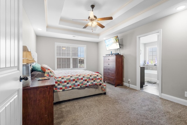 carpeted bedroom featuring multiple windows, ensuite bath, a raised ceiling, and baseboards