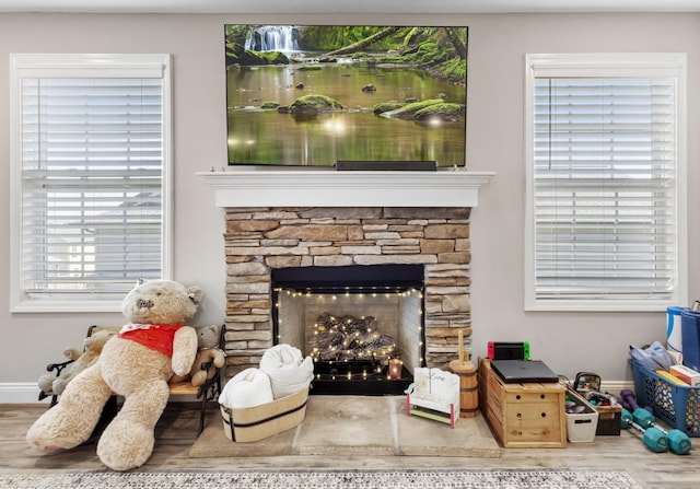 living area with a fireplace, baseboards, and wood finished floors