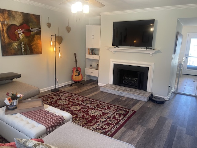 living area featuring a fireplace with raised hearth, wood finished floors, crown molding, baseboards, and ceiling fan