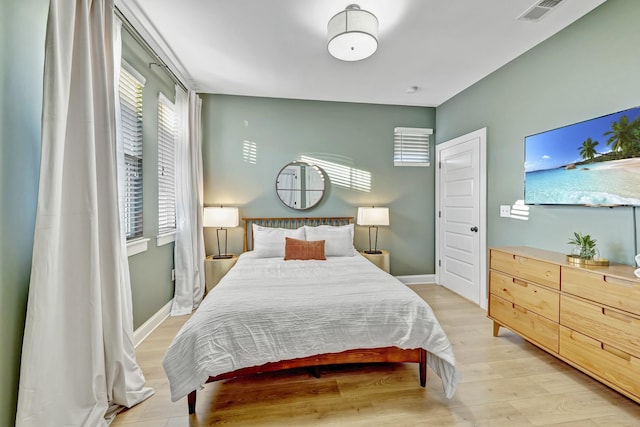 bedroom featuring light wood-style floors, visible vents, and baseboards