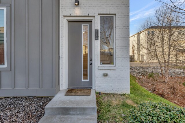 doorway to property with brick siding and board and batten siding