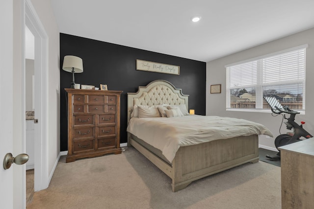 bedroom with an accent wall, baseboards, and light carpet