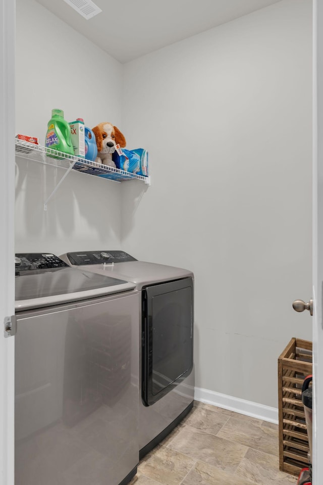 clothes washing area with laundry area, separate washer and dryer, and baseboards