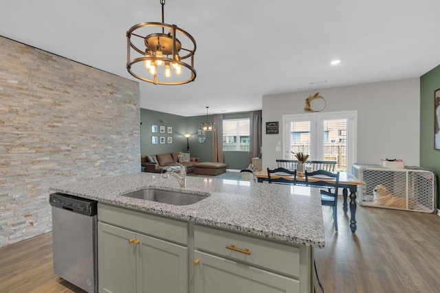 kitchen with a sink, open floor plan, light stone countertops, dishwasher, and a chandelier
