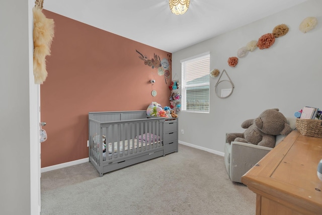 carpeted bedroom with baseboards and a nursery area