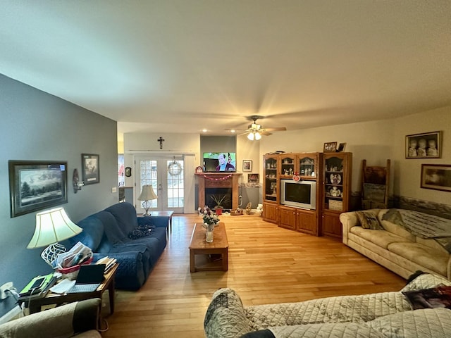 living room with french doors, a fireplace, and light wood-style floors