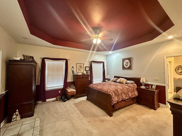 bedroom featuring a ceiling fan, a tray ceiling, and light colored carpet