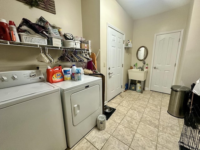 laundry room with baseboards, washing machine and dryer, laundry area, light tile patterned flooring, and a sink