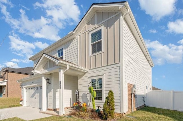 view of front of house featuring driveway, board and batten siding, an attached garage, and fence