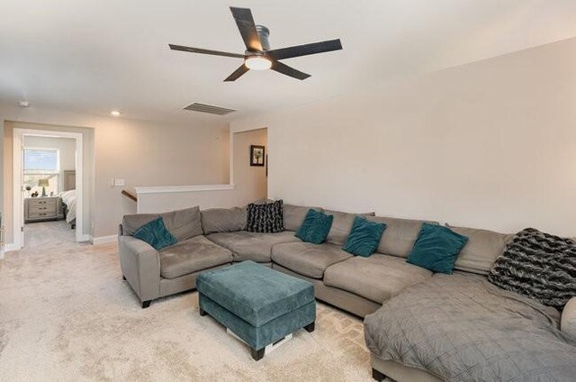living room featuring baseboards, a ceiling fan, visible vents, and light carpet