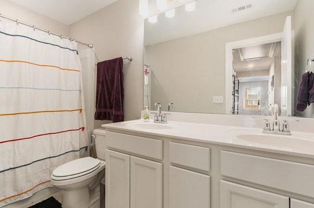 bathroom featuring double vanity, toilet, visible vents, and a sink