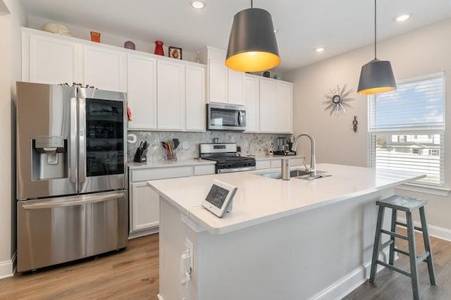 kitchen with decorative backsplash, appliances with stainless steel finishes, light wood-style floors, and a sink