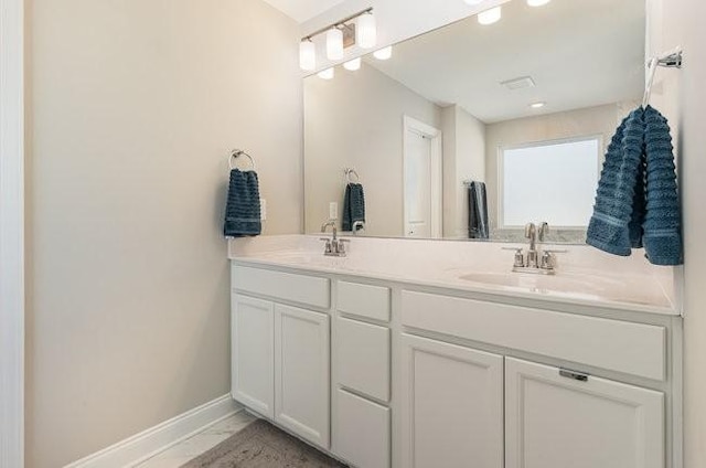 full bathroom featuring double vanity, marble finish floor, baseboards, and a sink