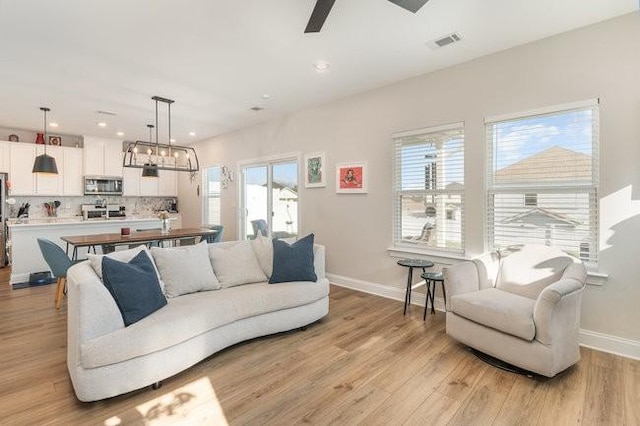 living area with recessed lighting, visible vents, baseboards, and light wood-style flooring