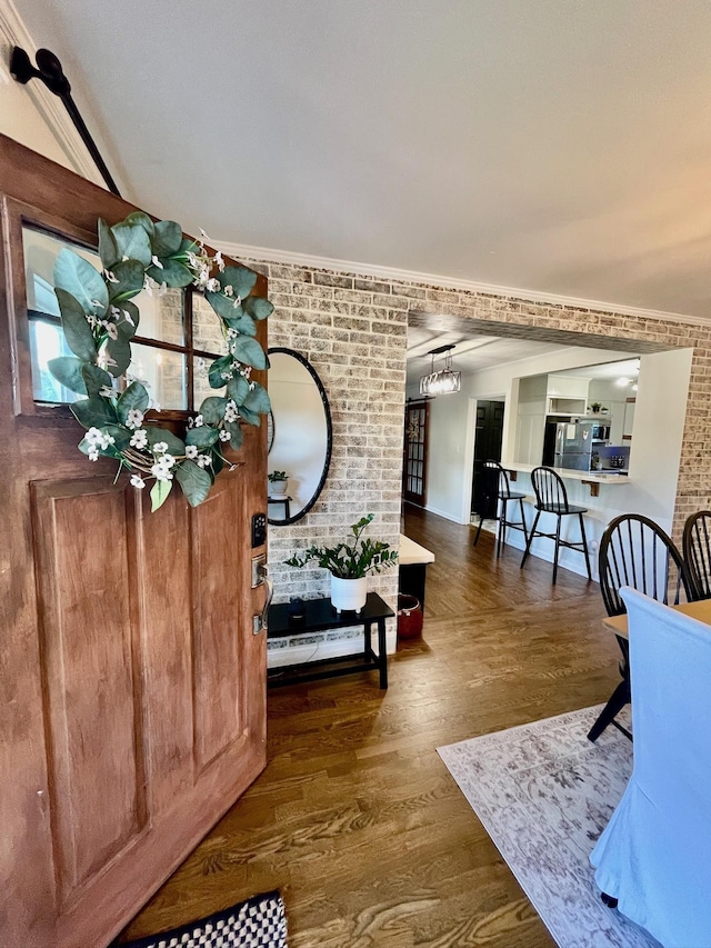 entryway with wood finished floors, brick wall, and a baseboard radiator