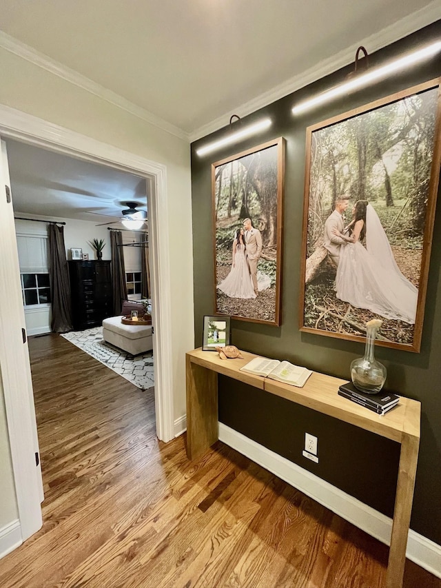 hallway with crown molding, baseboards, and wood finished floors