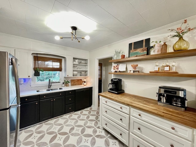 kitchen with a sink, open shelves, butcher block countertops, freestanding refrigerator, and dark cabinets