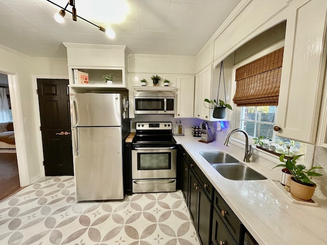 kitchen with dark cabinetry, open shelves, a sink, appliances with stainless steel finishes, and white cabinetry