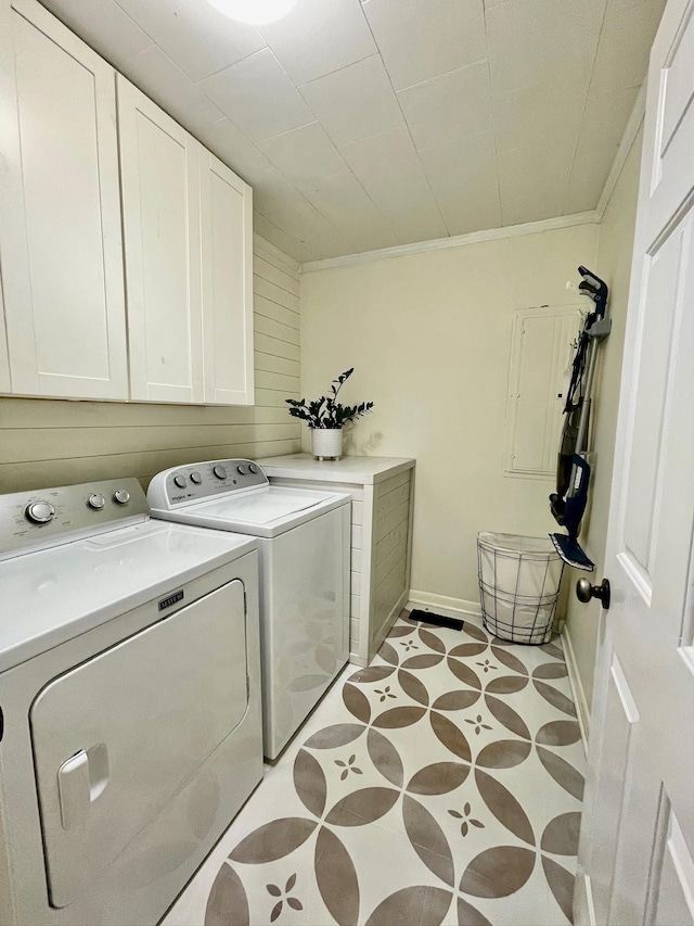 clothes washing area featuring washing machine and clothes dryer, wooden walls, crown molding, baseboards, and cabinet space