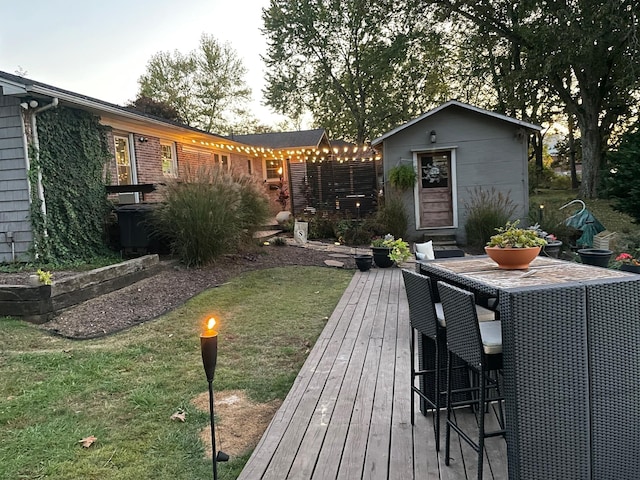 wooden deck featuring an outbuilding, outdoor dining area, and a lawn